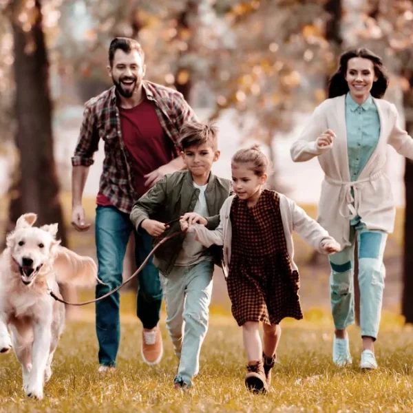 What does family mean to you? An image of a family and their dog out at the park.
